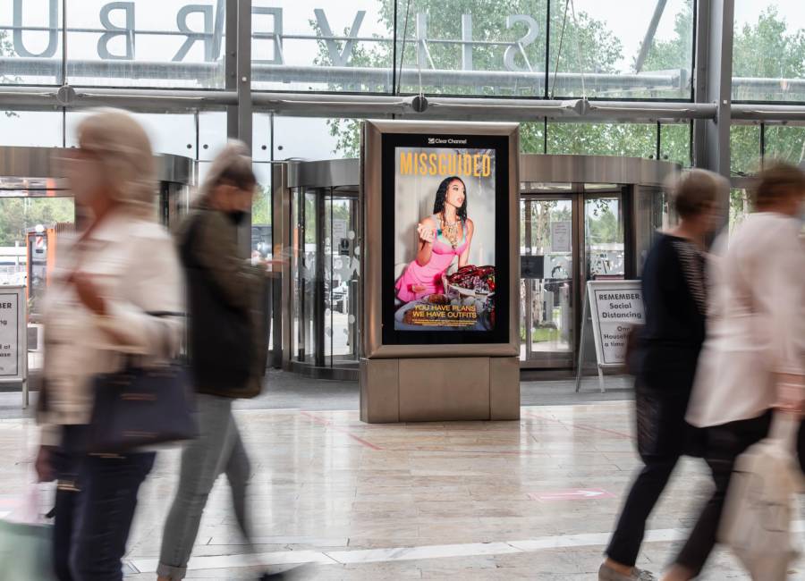 Missguided advert on digital screen in shopping mall with people walking past