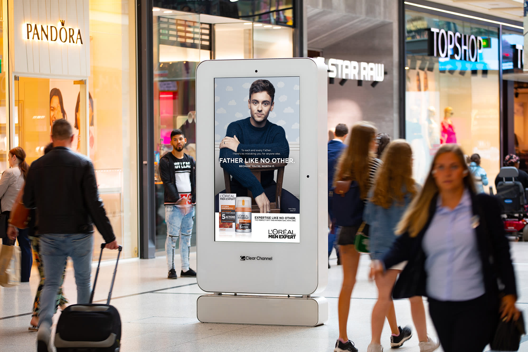 Loreal advert on digital screen in shopping mall with people walking past